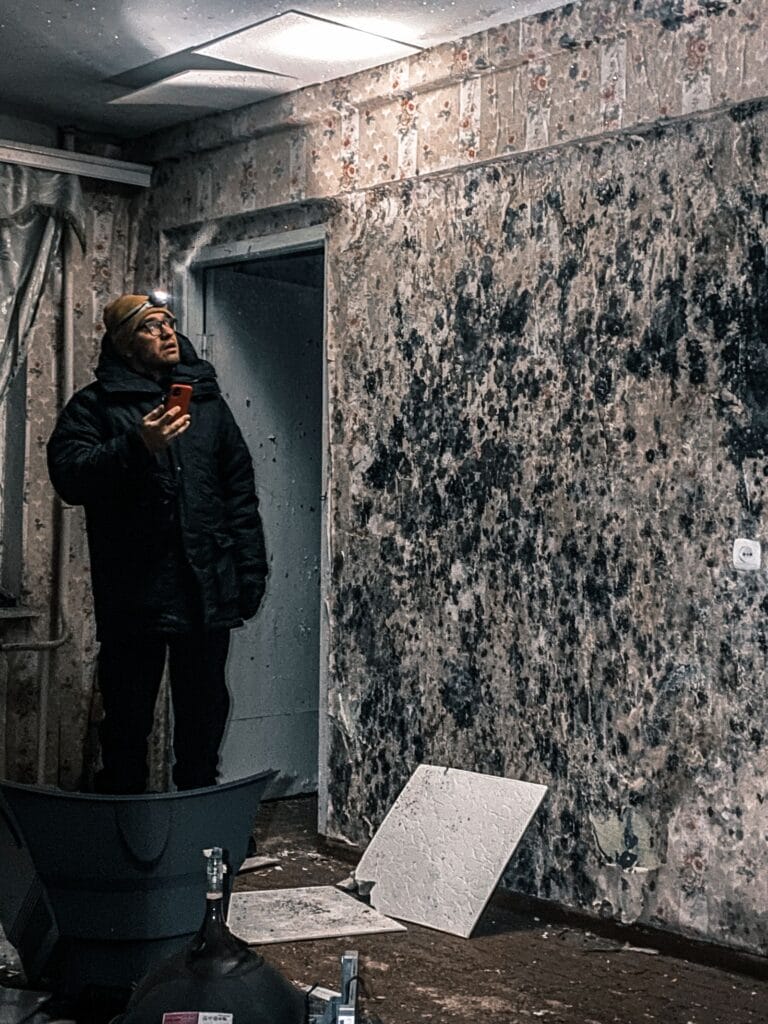 Technician inspecting a wall for mold growth in a Winnipeg house