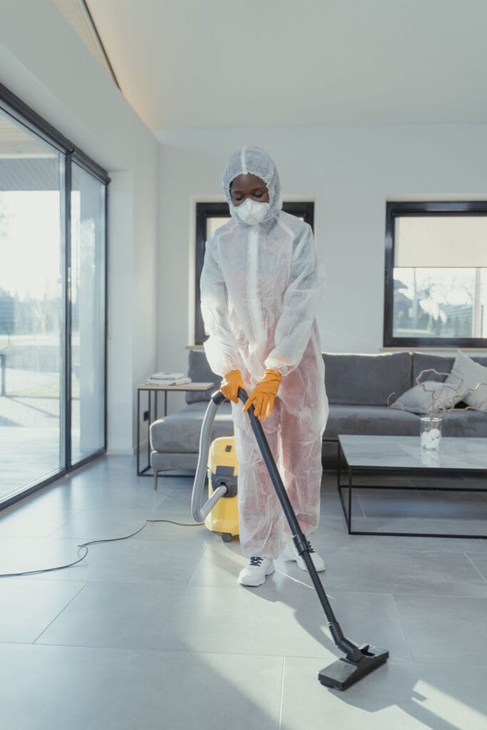 Restoration technician in full PPE cleaning a mold-affected area