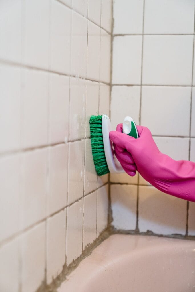 Technician scrubbing mold off bathroom tile grout in a Winnipeg home